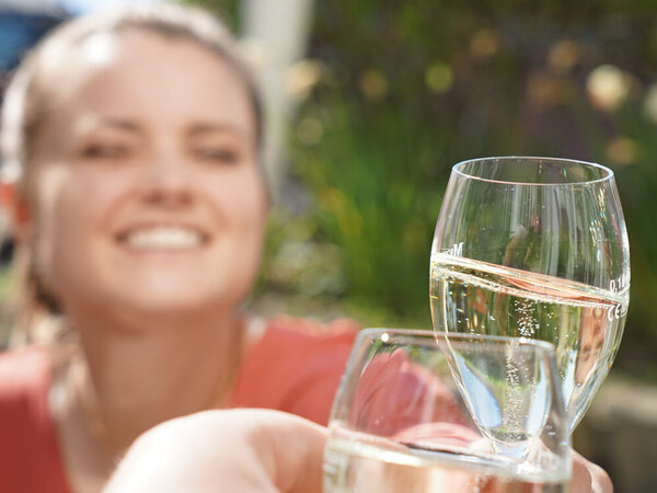 Eine junge Frau stößt mit einem Sektglas an